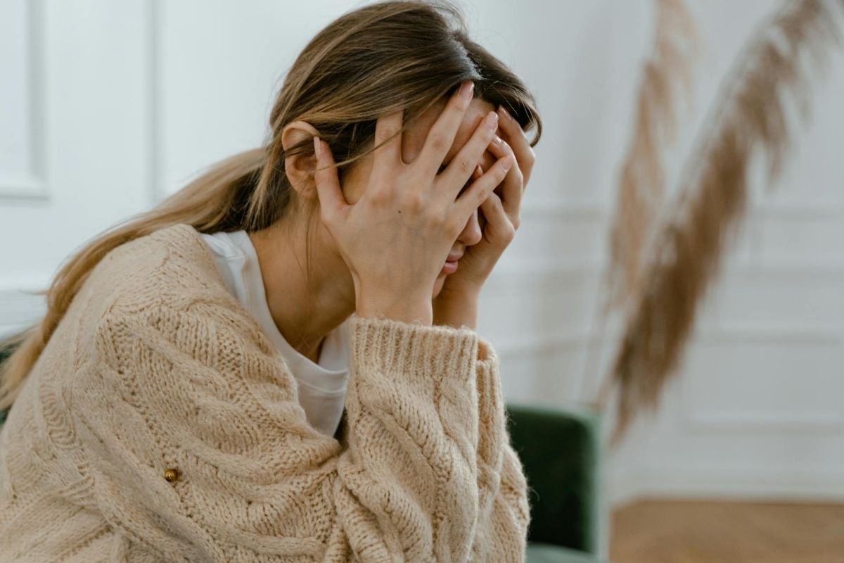 Polyvagal-Theorie und Nervensystem: Erschöpfte Frau stützt ihren Kopf in die Hände Polyvagal-Theorie und Nervensystem: Erschöpfte Frau stützt ihren Kopf in die Hände