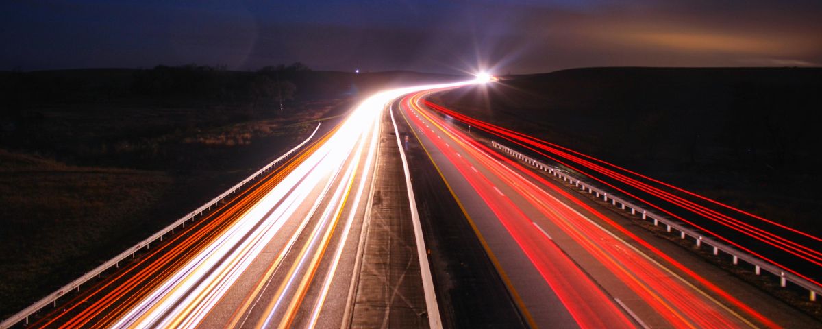 Autobahn bei Nacht mit roten und weißen Lichtspuren in Langzeitbelichtung